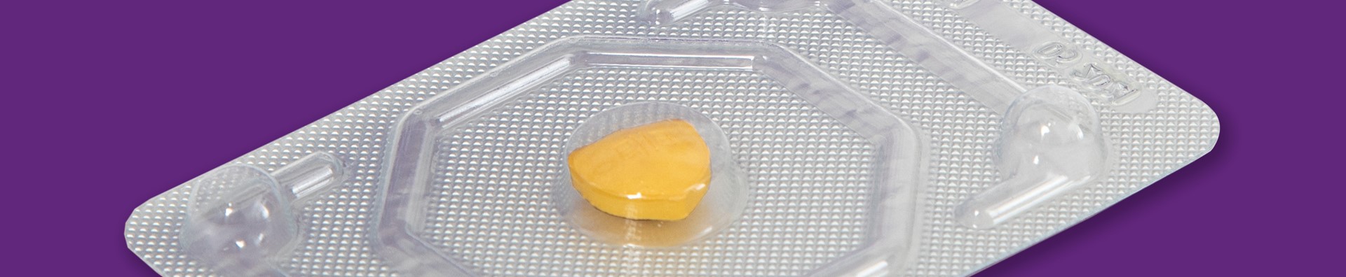 Photo of a single pill in a packet on a purple background