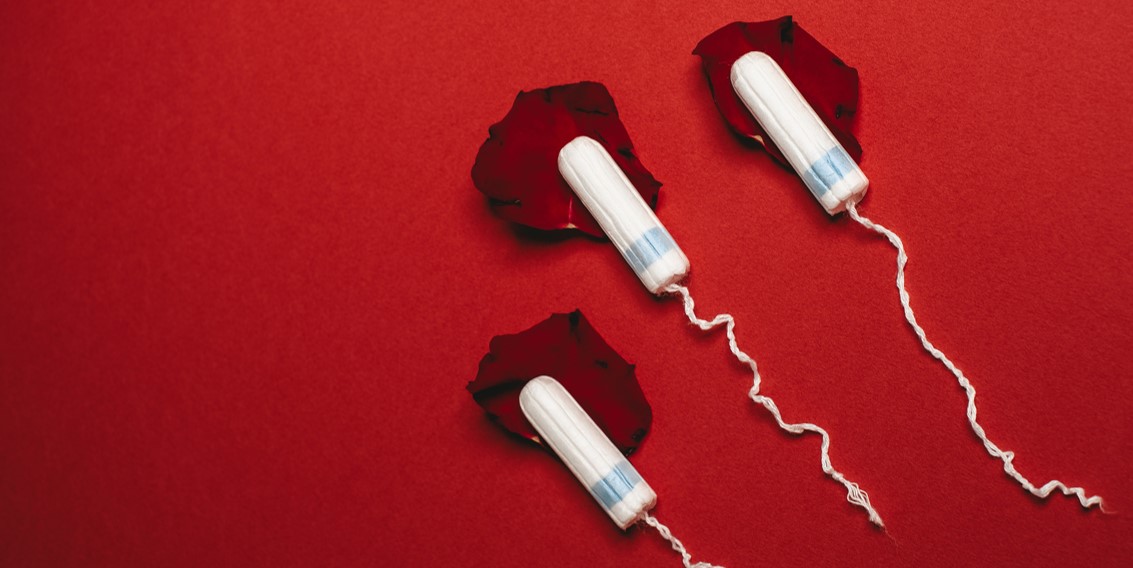 Three tampons on rose petals on a red background