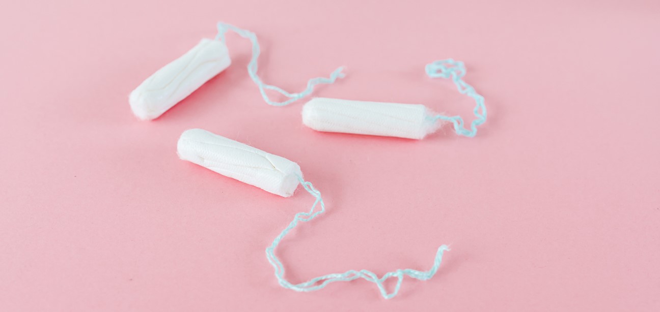 Photo of 3 unwrapped tampons on a pink background