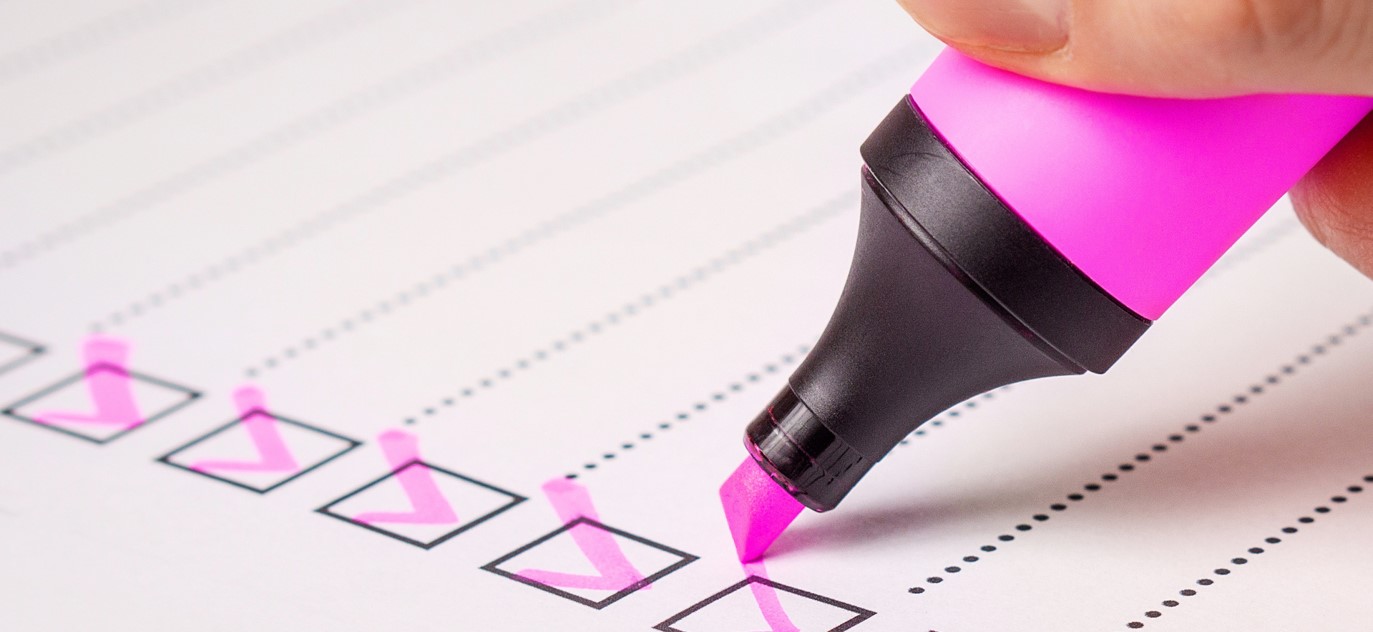 Photo of a pink highlighter ticking boxes on lined paper