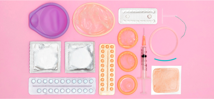 Photo of various contraceptive devices on a pink background