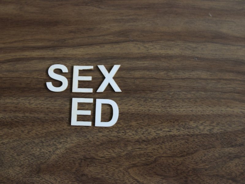 photo of white letters on a wooden background stating "Sex Ed"