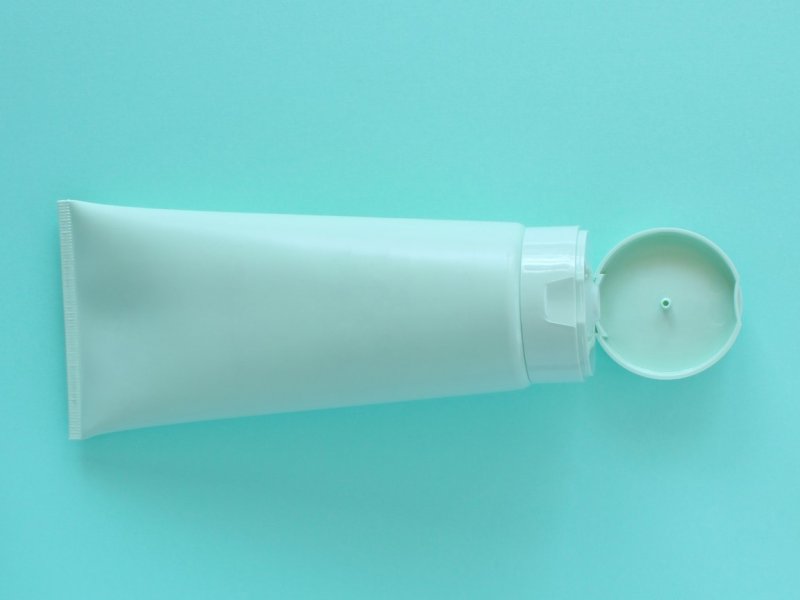 Photo of a tube of lube on an aquamarine background.