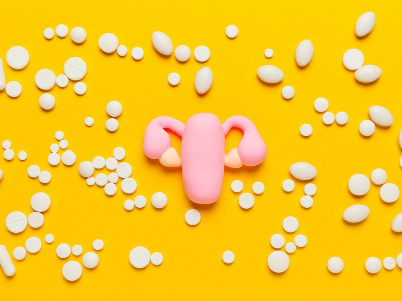 Photo of a model uterus on a yellow background with medications surrounding