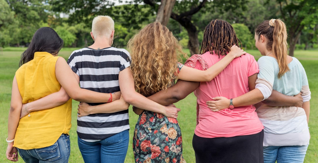 Photograph of five people with their arms around each others' backs
